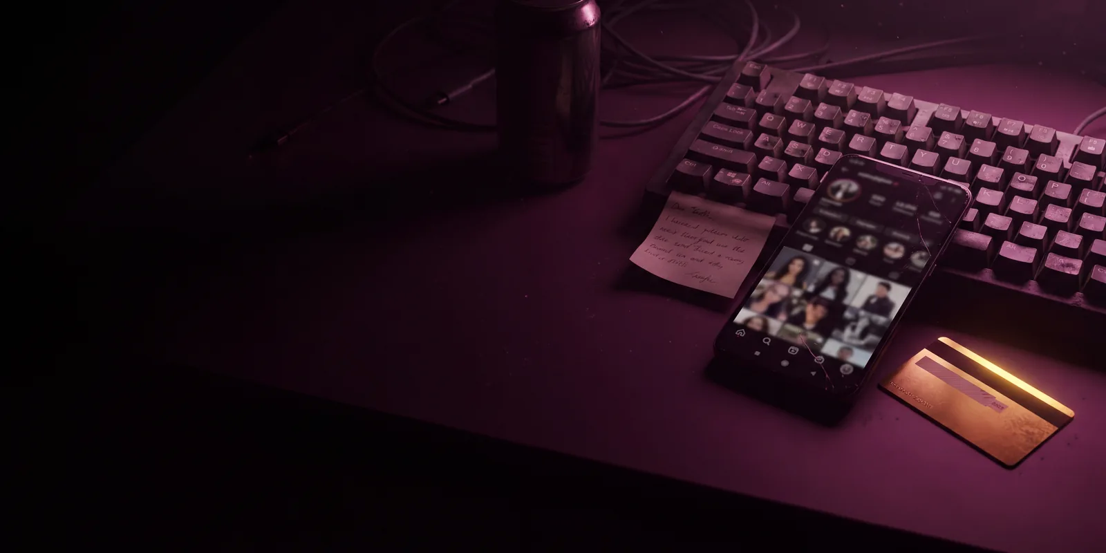 The Recruit: a dim desk with a keyboard, a phone open on a social profile, a sticky note and a bank card